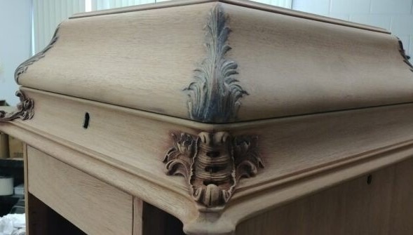 The deteriorated finish of the antique phonograph was stripped to reveal the wood beneath.