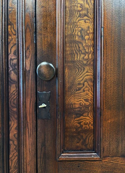 An interior view of a 19th century wood wardrobe with opened door and hooks before restoration.