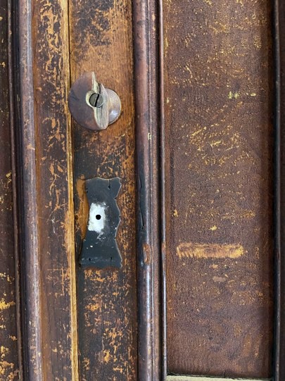 Detail of a 19th century wardrobe showing a broken wood knob and hardware before restoration